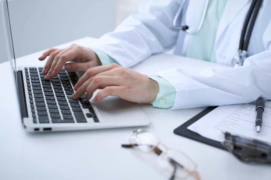 Close-up-of-a-female-doctor-typing-on-laptop-computer,-sitting-at-the-table-in-the-hospital-867698684_2125x1416-1